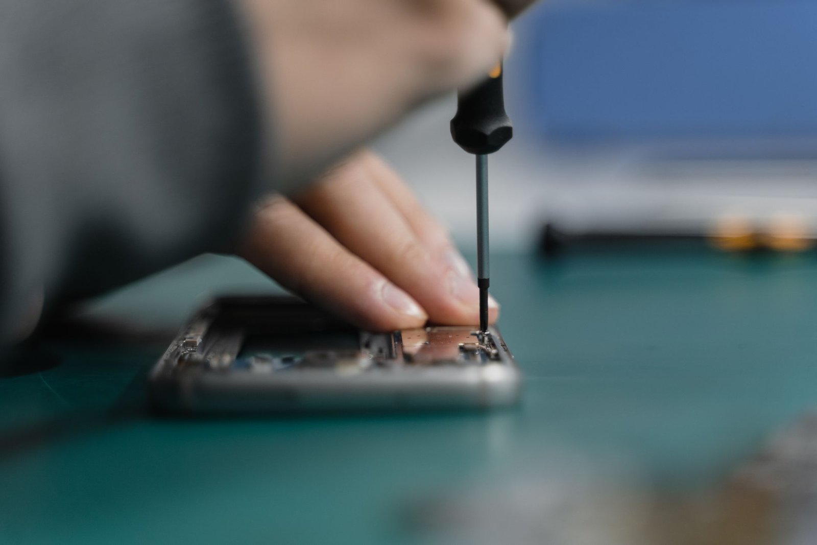 Technician repairing a small mobile device with precision tools