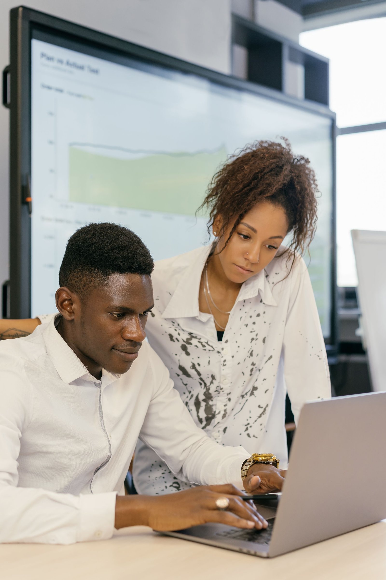 Two colleagues working together at a laptop in a small office