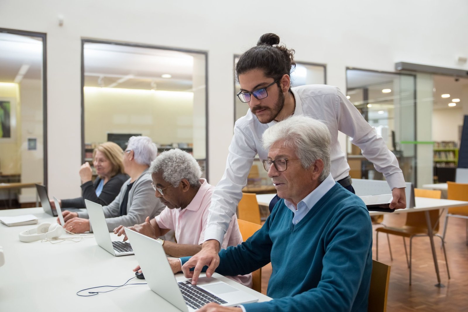 An instructor helping an adult learner use a desktop computer